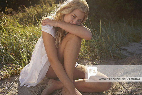 Junge Frau sitzt am Rande des Strandes.
