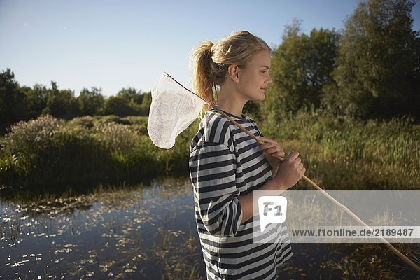 Junge Frau am Teich mit Fischernetz.