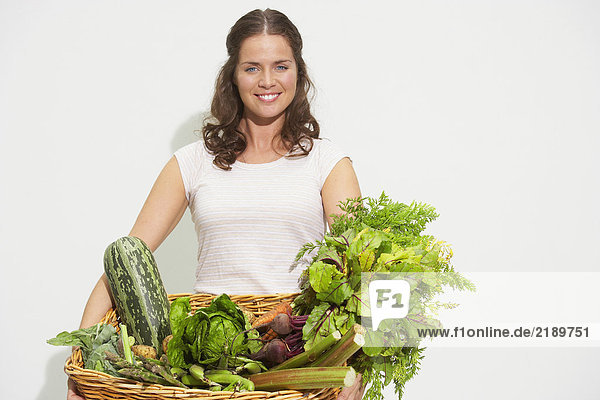 Junge Frau mit großem Korb mit Bio-Gemüse.