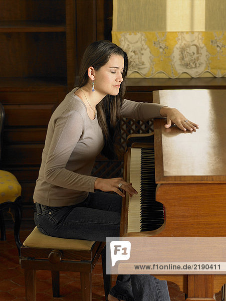 Junge Frau spielt Klavier mit einer Hand  Augen geschlossen