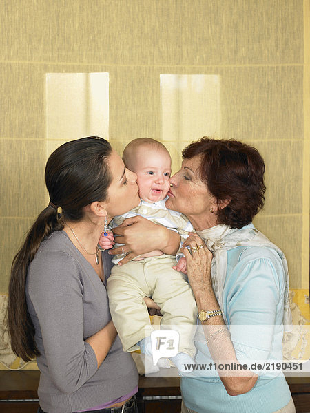 Mutter und Großmutter küssen Jungen (1-3 Monate)