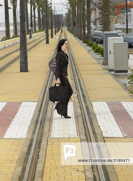 Geschäftsfrau  die mit der Straßenbahn über den Fußgängerüberweg läuft