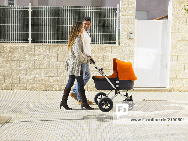 Couple walking with pram on pavement  Alicante  Spain