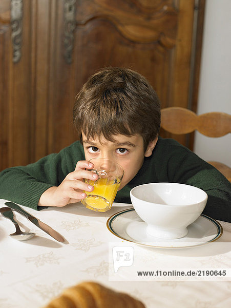 Boy (6-8) drinking orange juice at breakfast  portrait