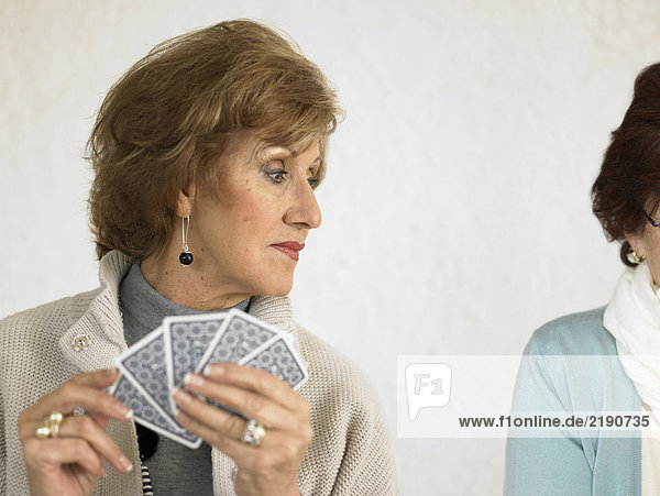 Zwei ältere Frauen spielen Karten  eine schaut über die Schulter