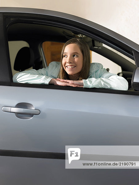 Girl (12-14) sitting in car  leaning out of window  smiling