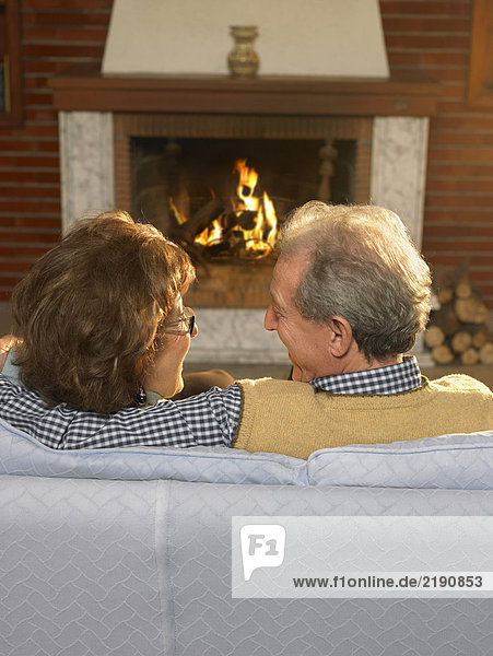 Seniorenpaar auf einer Couch vor dem Feuer  Nahaufnahme  Rückansicht. Alicante  Spanien.