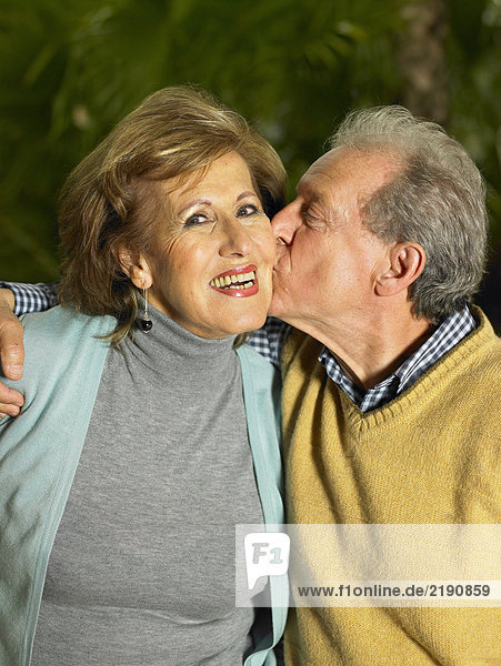 Seniorin wird vom Senior geküsst  lächelnd  Porträt