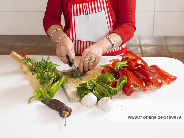 Reife Frau beim Gemüsehacken in der Küche  Mittelteil