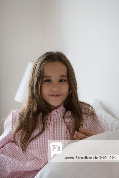 Young girl sitting on a bed portrait.