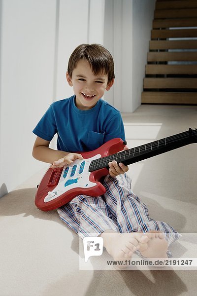 Portrait of a boy with toy guitar.