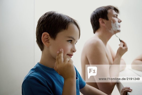 Mann rasiert sich mit Sohn.