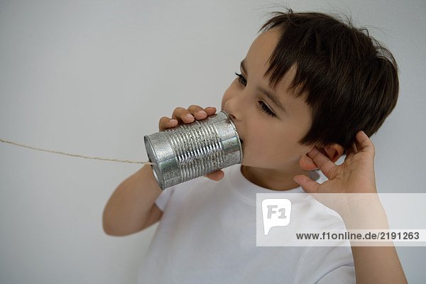 Boy using a tin can as a phone.