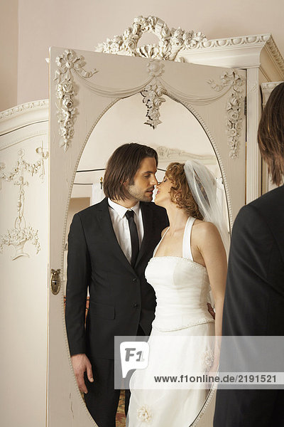 junges Brautpaar küssend im Garderobenspiegel reflektiert