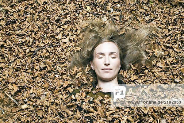 Young woman lying down on leafs.