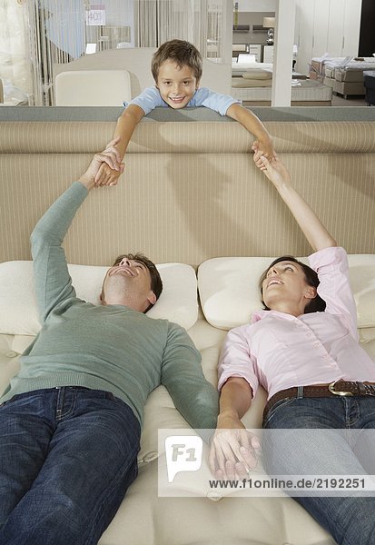 Couple lying on bed in a shop with son.