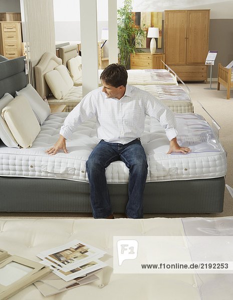 Man sitting on bed in furniture store.