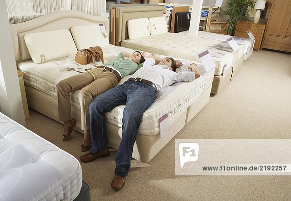 Couple lying on bed in furniture store.