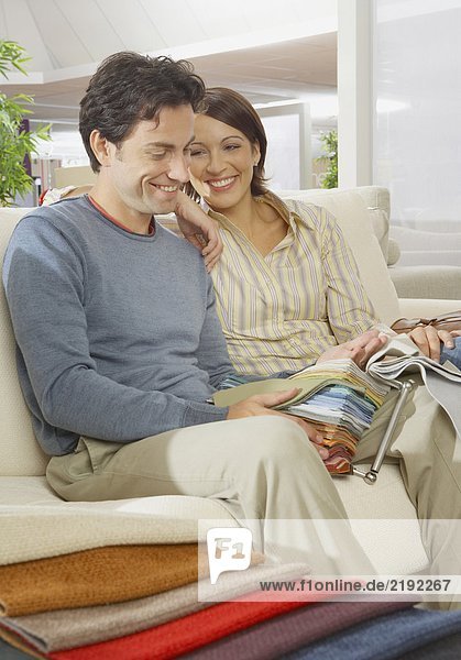 Couple sitting on sofa in furniture shop.