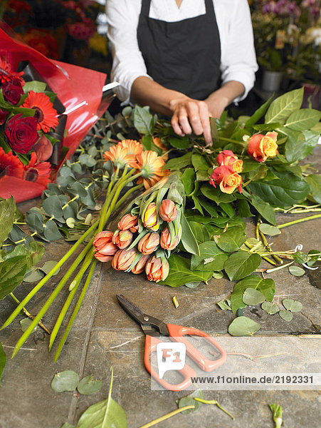 Junge Floristin bereitet Blumenstrauß im Geschäft vor  Mittelteil
