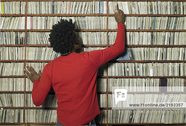 Mann wählt Compact Disc aus dem Regal im Musikgeschäft  Rückansicht