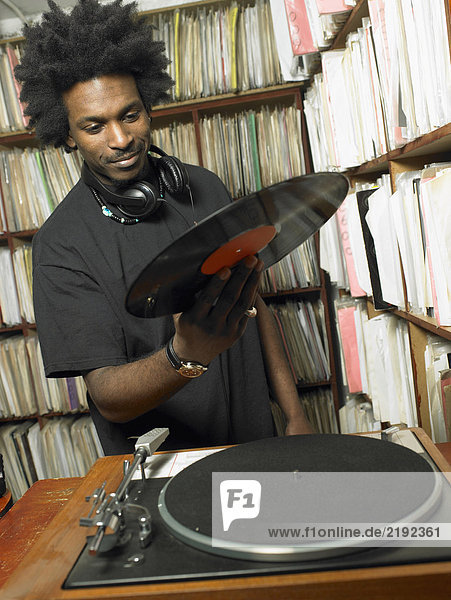 Männlicher DJ mit Schallplatte im Musikladen  lächelnd