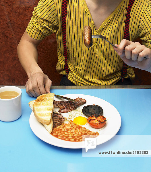 Junger Mann isst gebratenes Frühstück im Cafe  Mittelteil