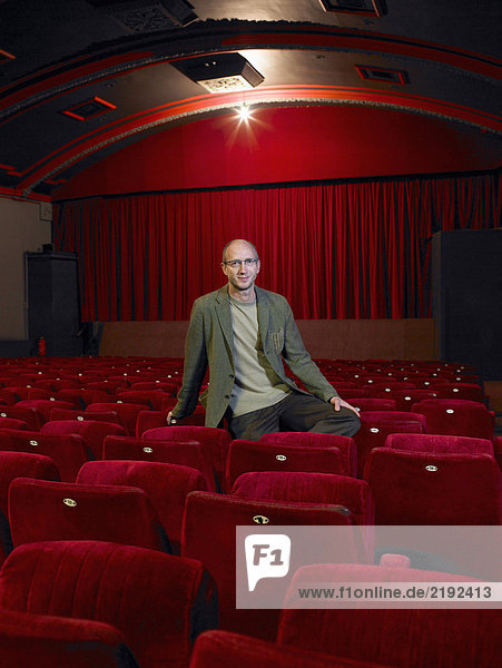 Reifer Mann im leeren Kino sitzend lächelnd Portrait