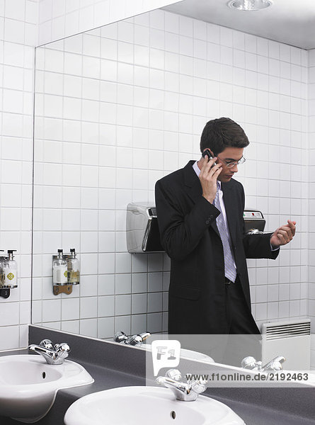 Der Mensch spiegelt sich im Büro-Waschraumspiegel mit dem Handy wider.