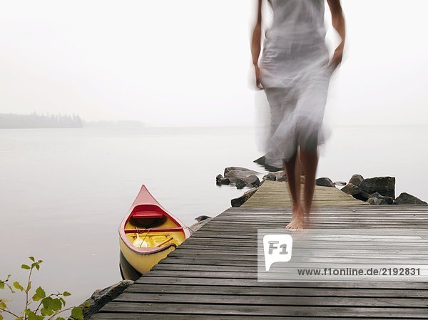 Eine Frau, die auf einem Dock in der Nähe eines Bootes läuft.