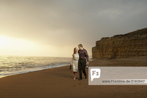 Mann und Frau schlendern am Strand entlang.
