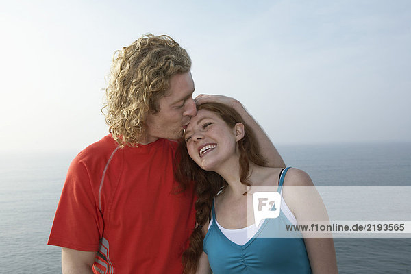 Porträt eines jungen Mannes  der eine Frau küsst.