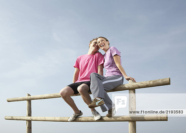 Ein junges Paar sitzt auf einem Zaun.