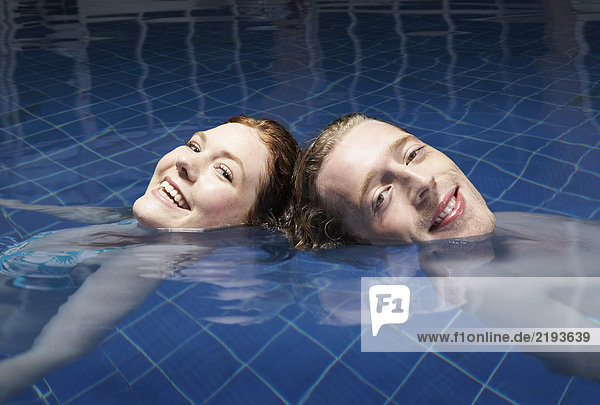 Mann und Frau schwimmen in einem Pool.