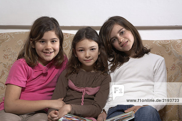 Three girls (5-11) sitting on a sofa  portrait