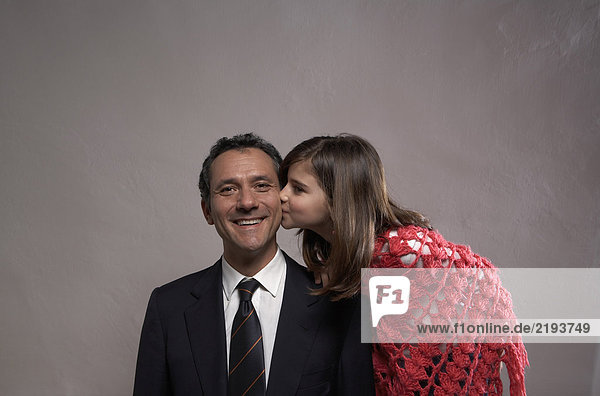Tochter (9-11) küsst lächelnden Vater auf die Wange