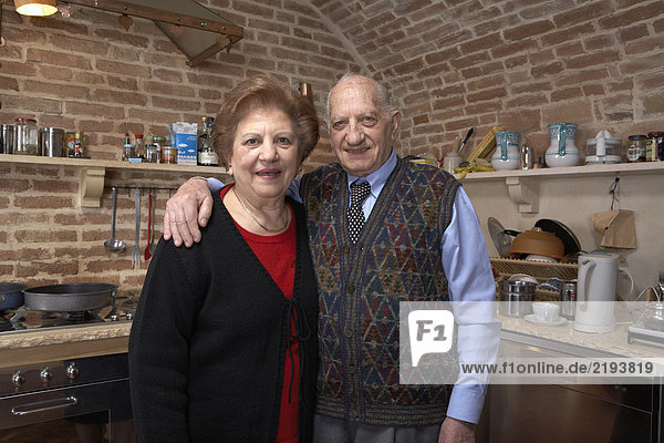 Senior couple in kitchen  smiling  portrait