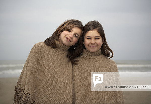 Zwei Schwestern (6-11) am Strand stehend  Portrait