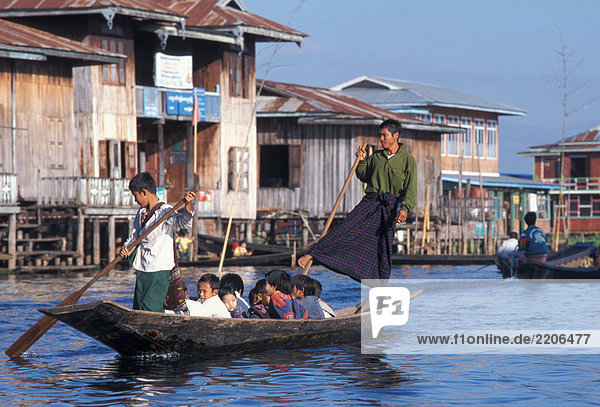 Burma  Inle Lake  man transporting children in boat