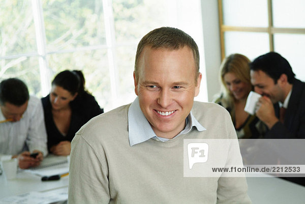 Happy businessman in front of colleagues