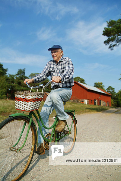 Elderly man biking on road