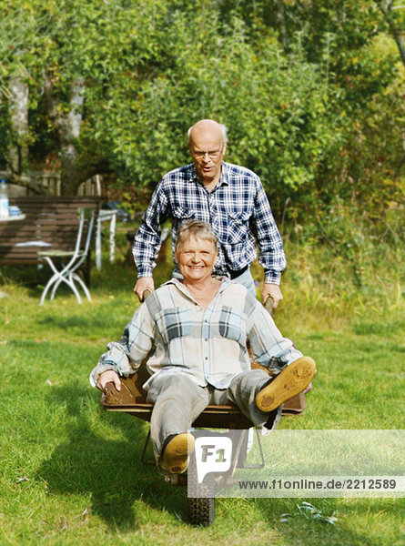 Elderly man with wife in wheelbarrow