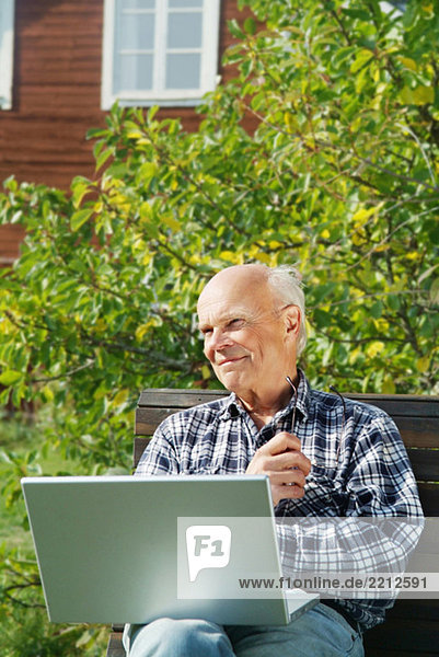 Älterer Mann am Computer im Freien