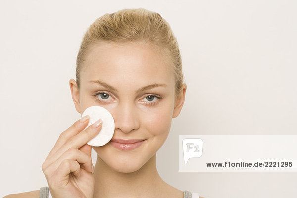Young woman using cotton pad on face  portrait