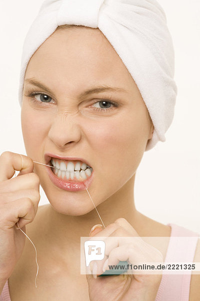 Nahaufnahme einer jungen Frau  die ihre Zähne mit Zahnseide pflegt.