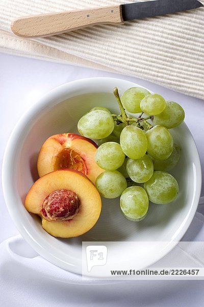 Nahaufnahme der Pfirsich Hälften und Trauben in Schüssel