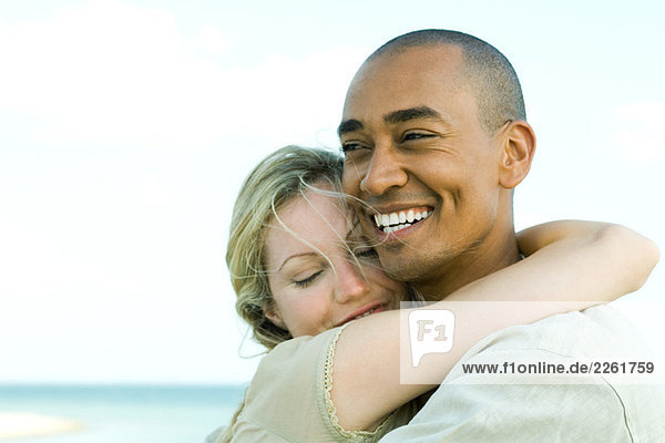 Couple embracing and smiling outdoors  woman's eyes closed