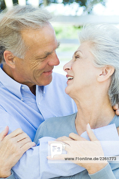 Mature couple embracing  smiling at each other  close-up