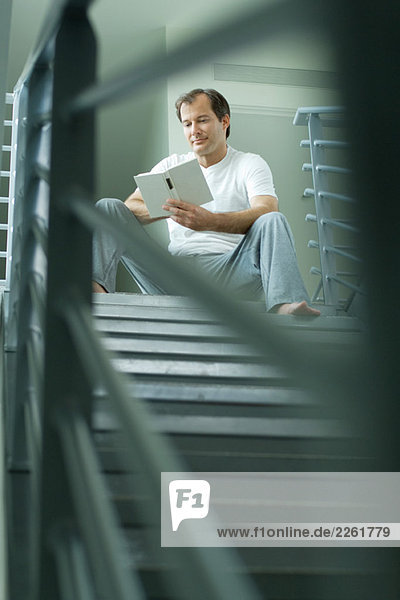Mann sitzt oben auf der Treppe Lesebuch  selektive Fokussierung