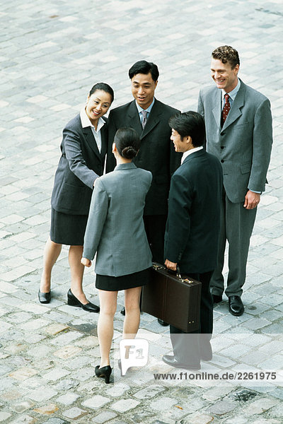 Group of professionals standing together  two women shaking hands  high angle view
